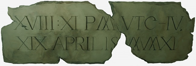 A wooden sculpture painted to look like cracked and broken stone with roman numerals carved into it